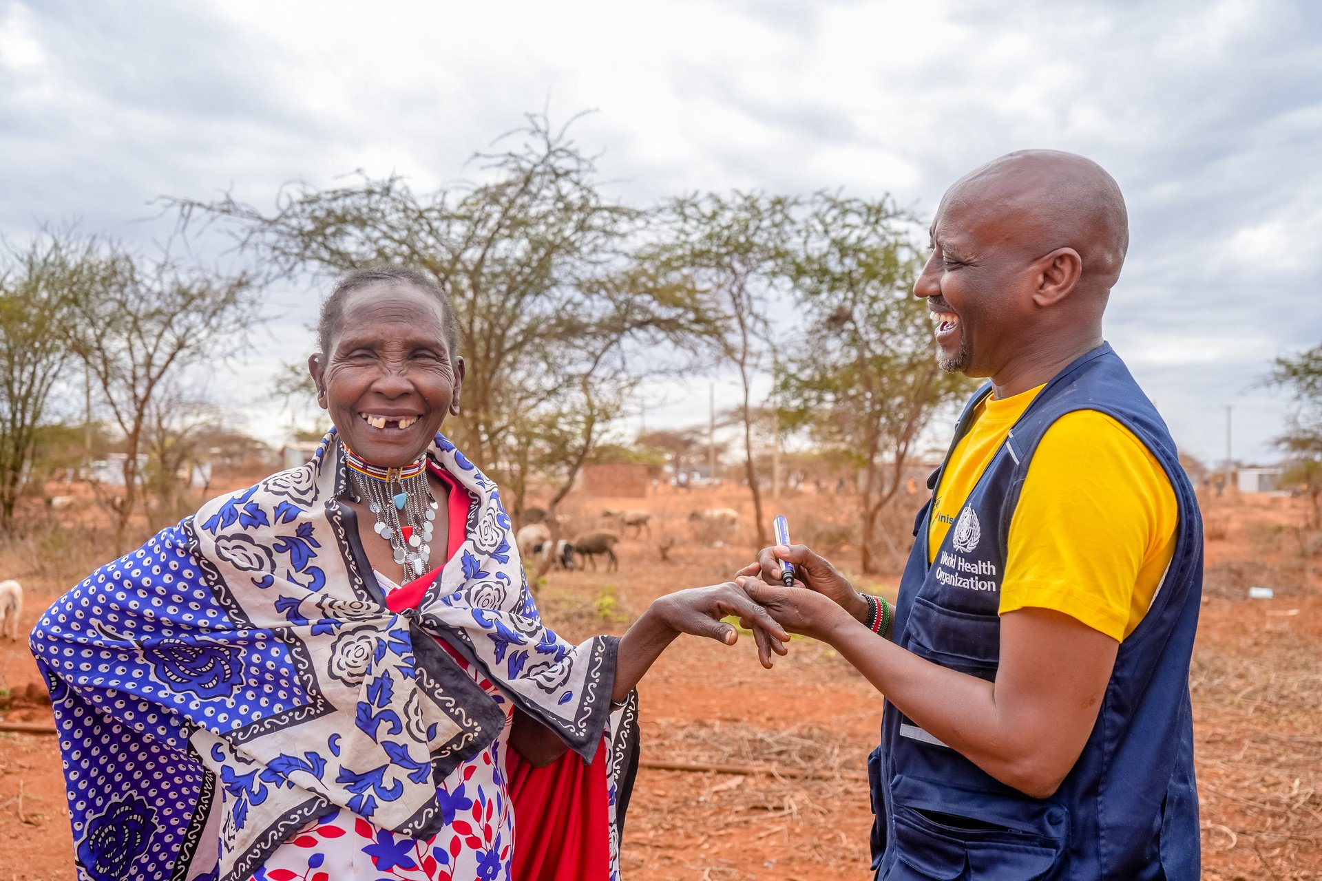 A woman from a Maasai community laughs with a WHO health worker