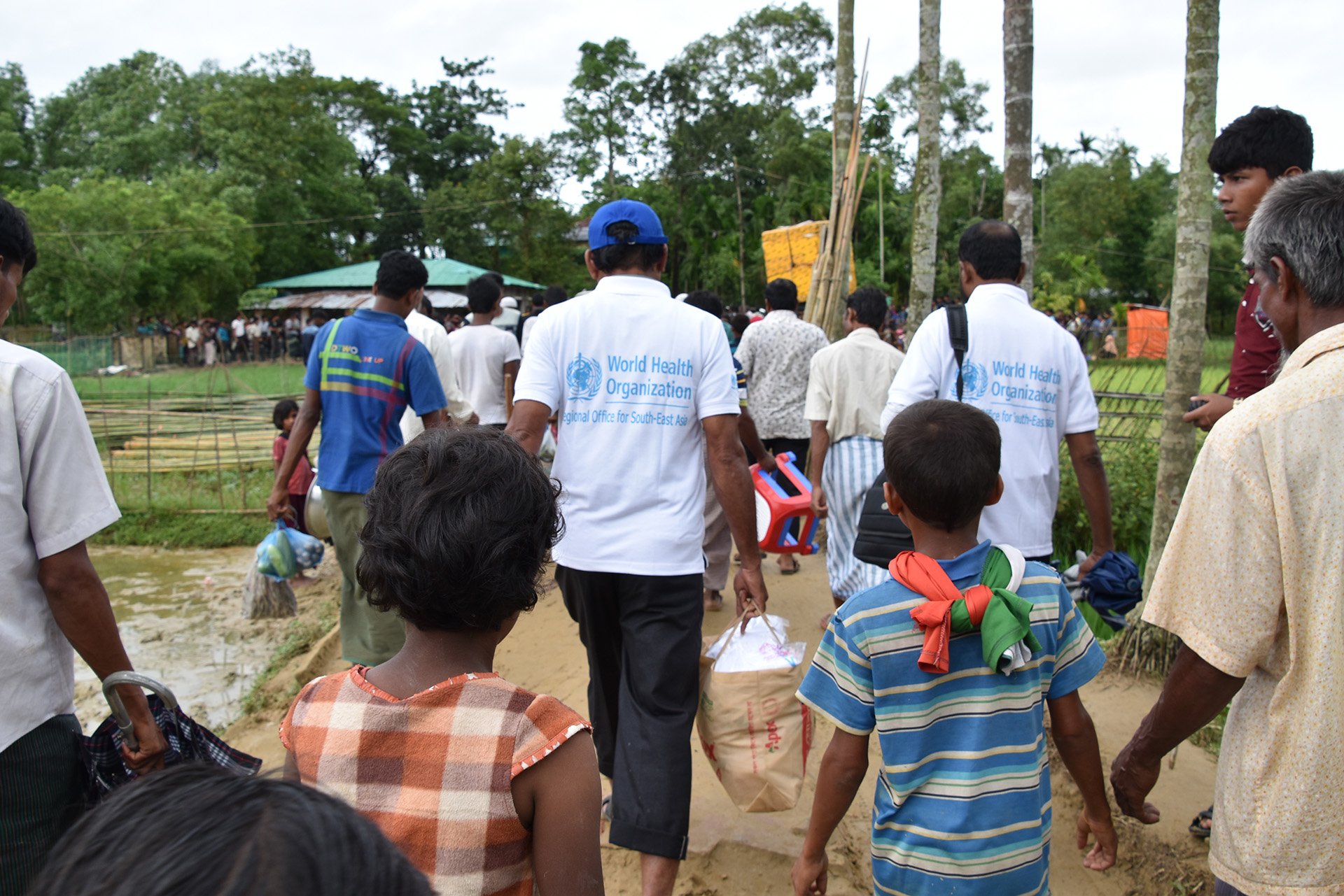 a group of people including some children walking with their backs to the camera