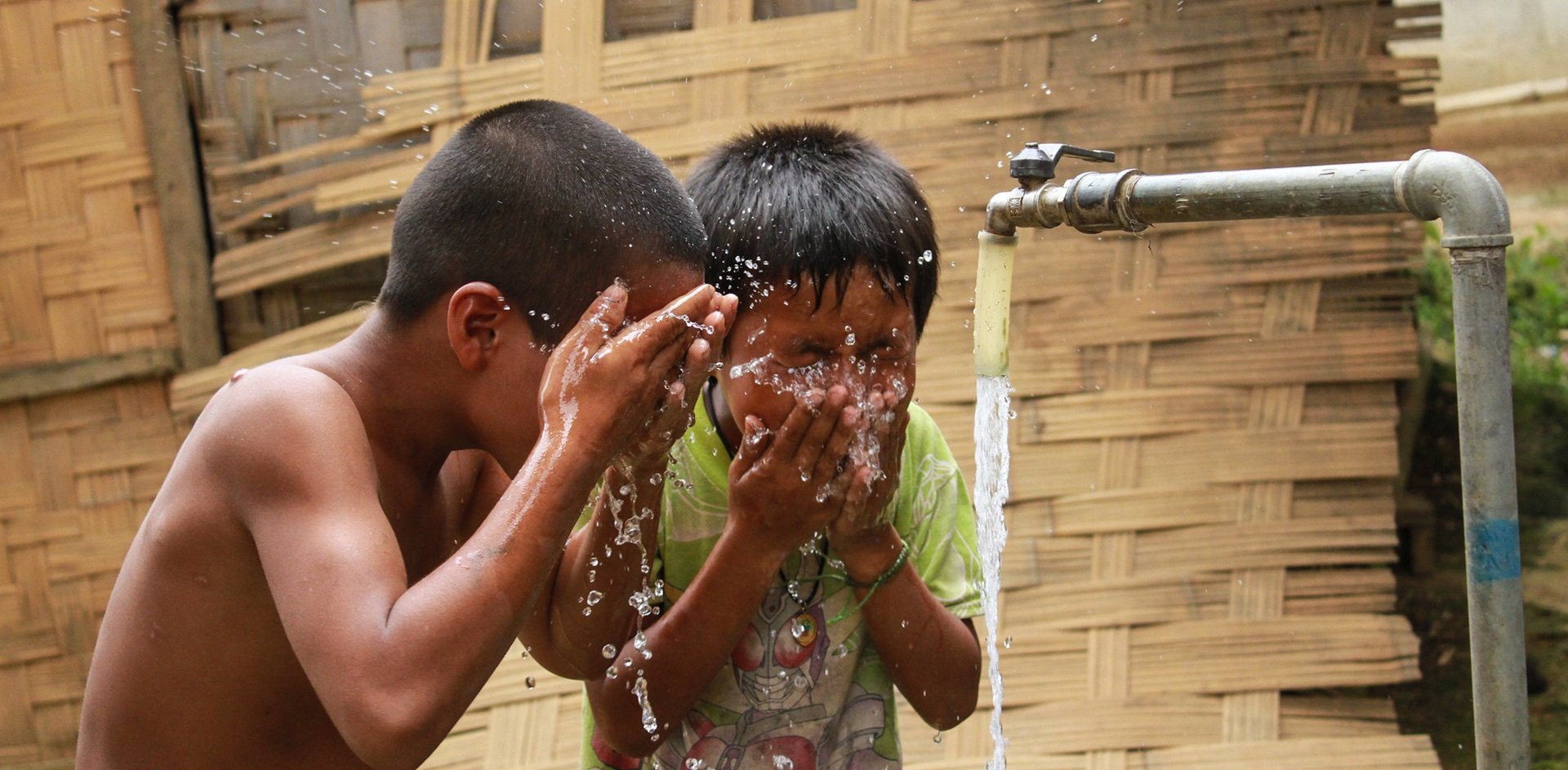 2 children wash at a water tap