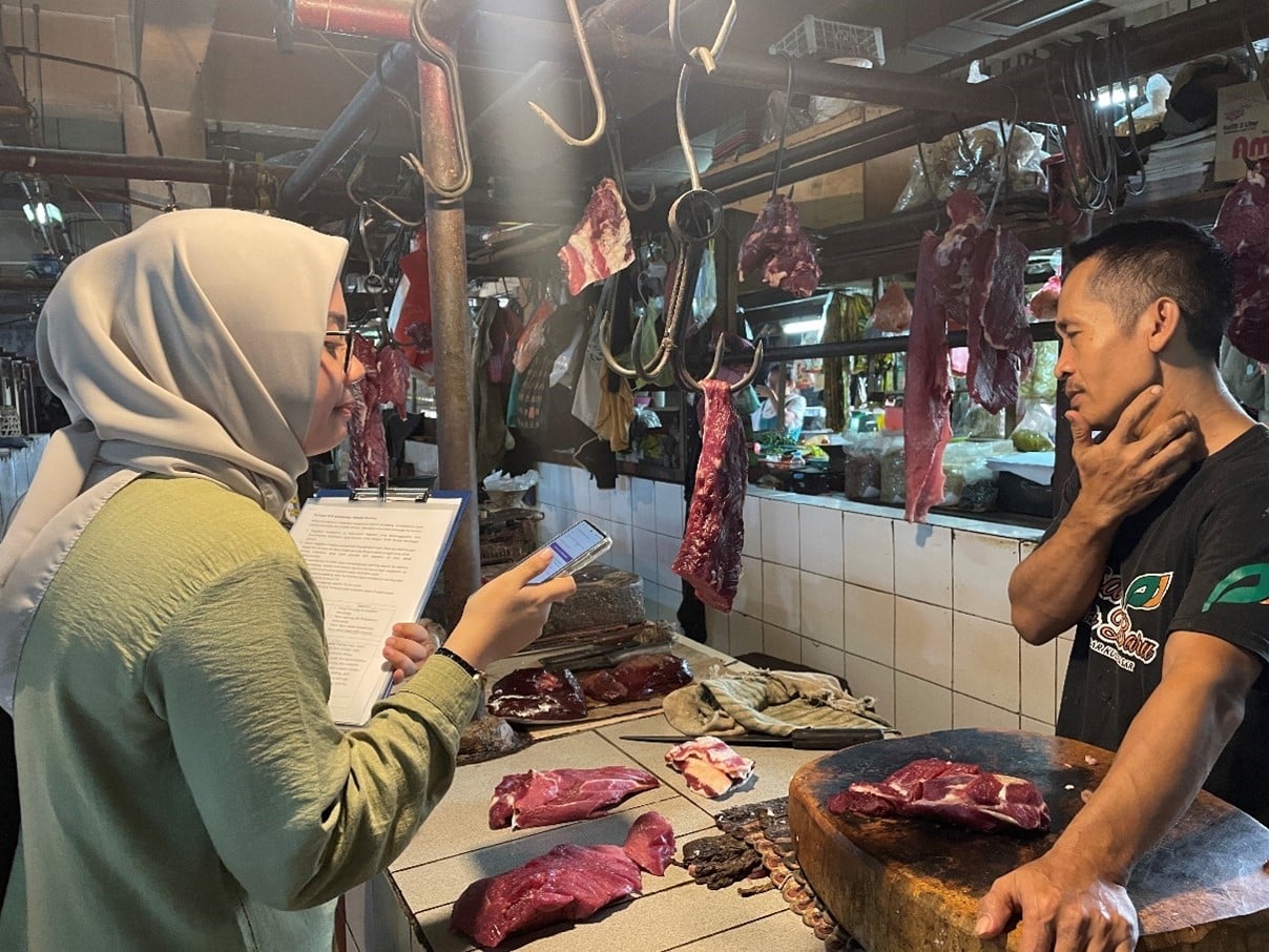 A woman in headscarf from WHO team in discussion with a meat seller in a wet market